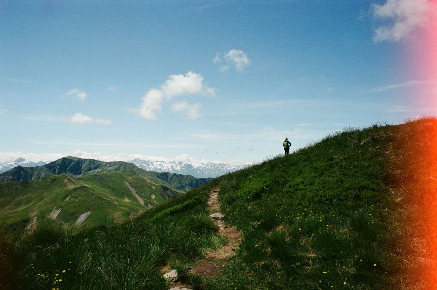 A lone figure on a green ridge, film flare at the edge